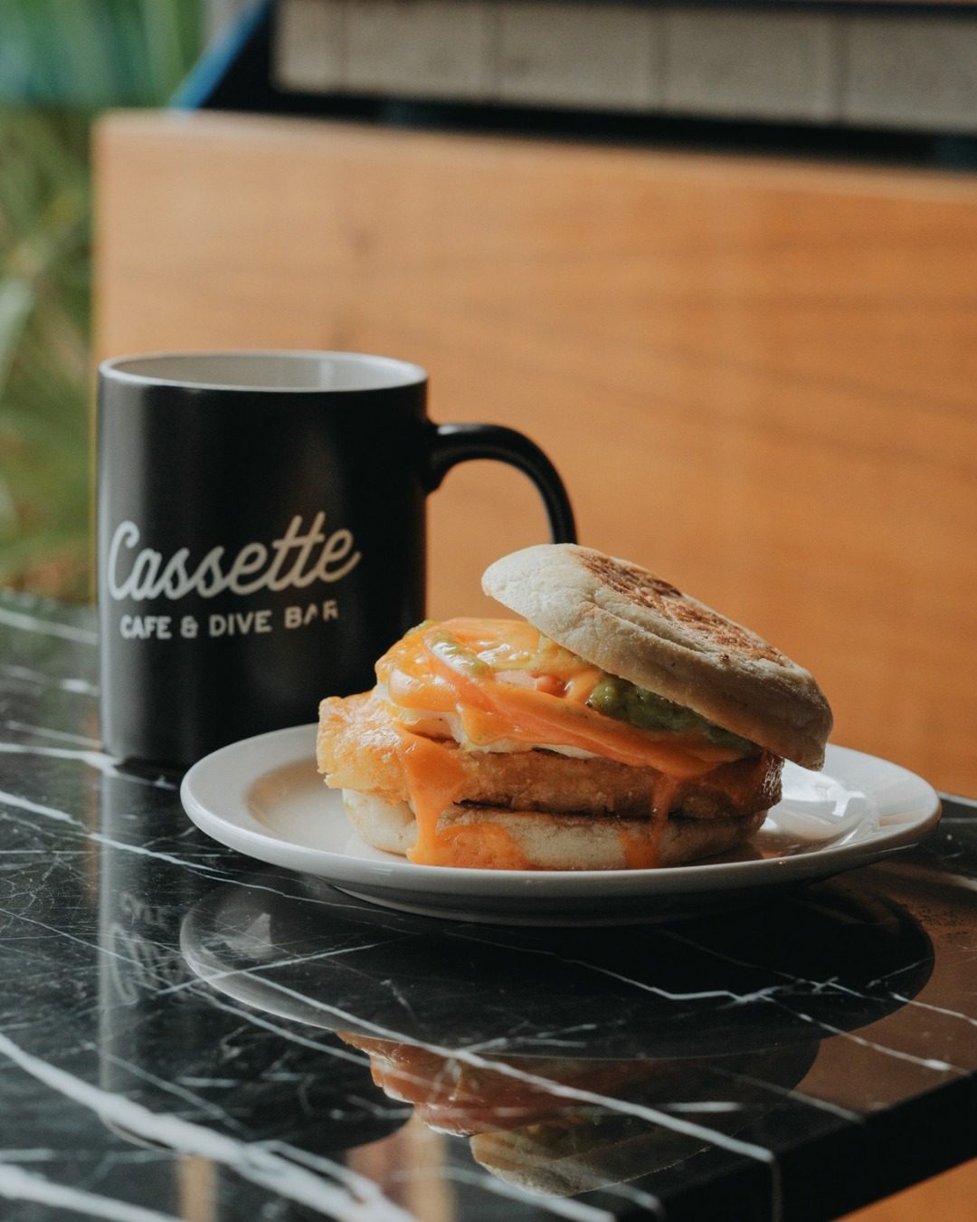A Cassette mug next to a breakfast sandwich