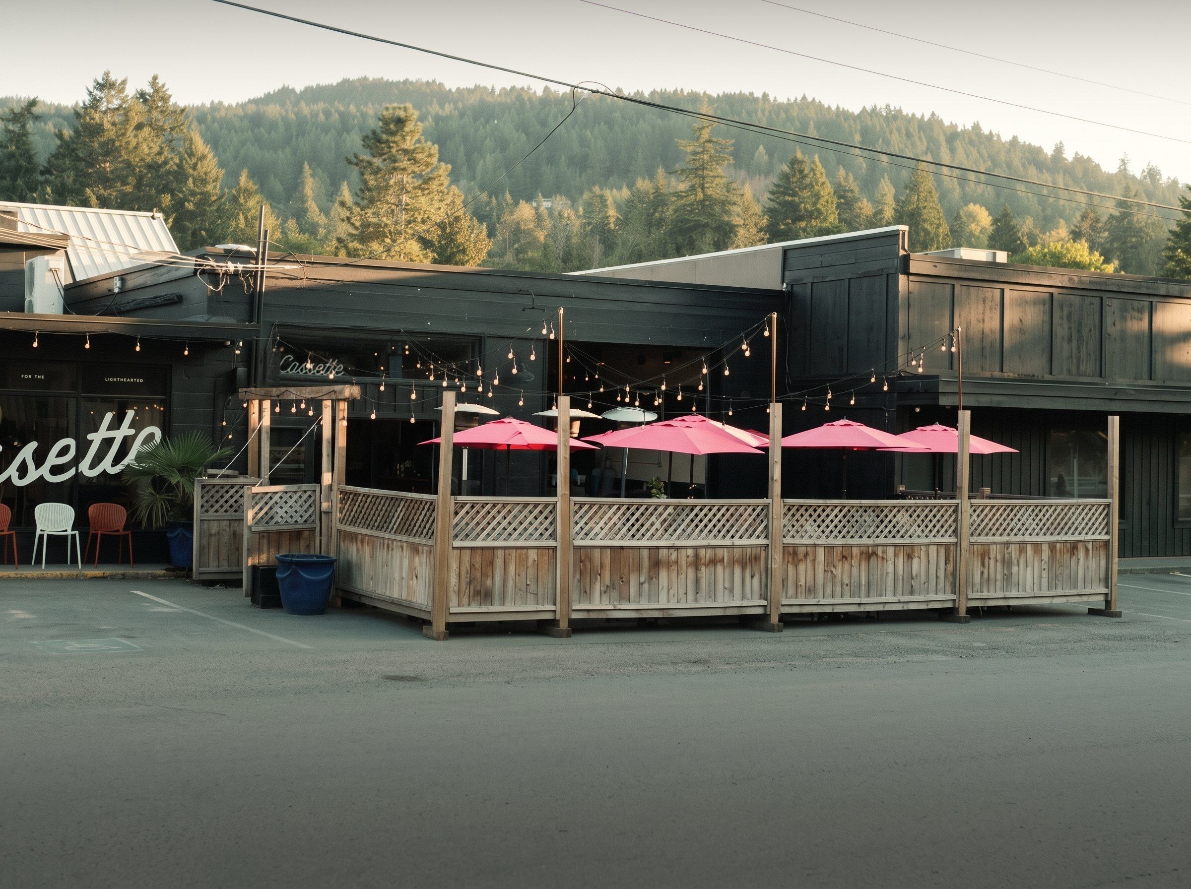 The Cassette patio in late afternoon sun, pink umbrellas up and the hill behind